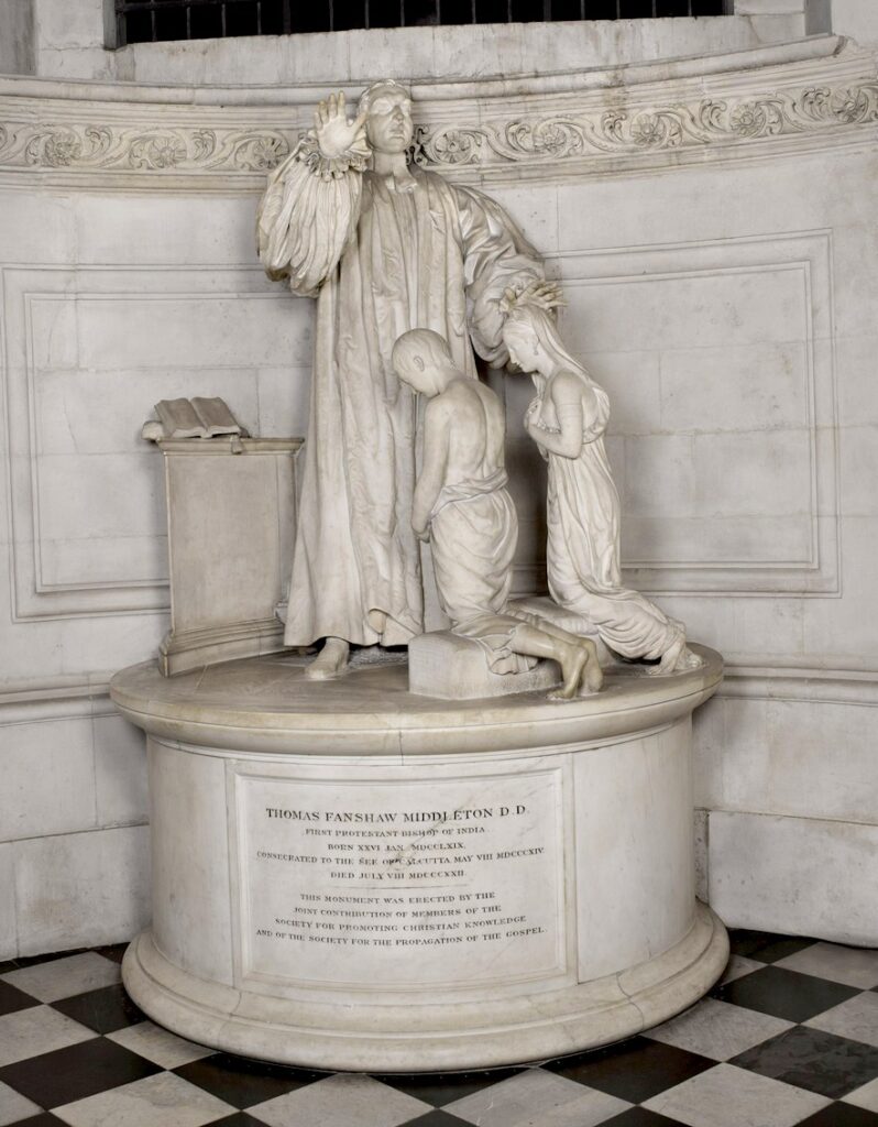 marble monument of a Bishop with one and raised and the other held over the bowed heads of two kneeling children.