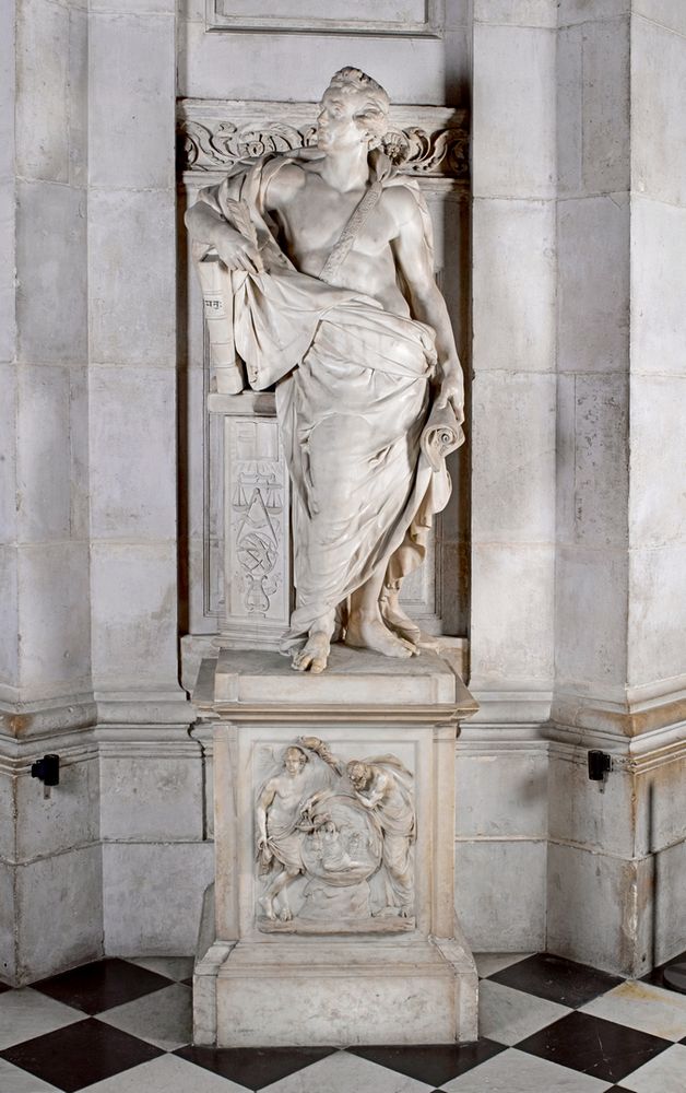White marble figure of a man wearing a toag-like garment, holding a book and standing on a plinth with a relief sculpted panel