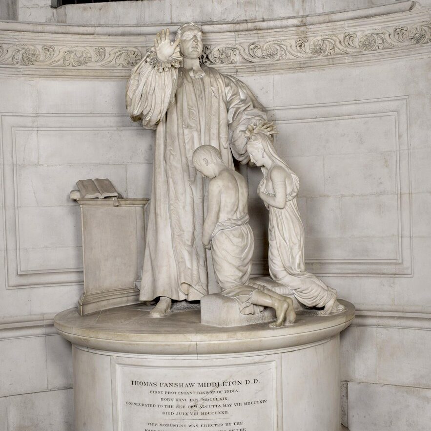 marble monument of a Bishop with one and raised and the other held over the bowed heads of two kneeling children.