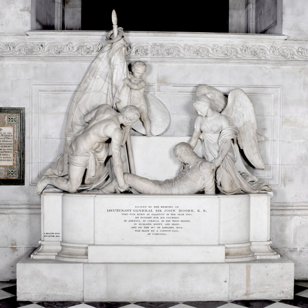 Marble monument with a figure being lifted onto a tomb by a robust male figure ('Courage') at his feet and an angel at his head. A cherub holding a standard looks down at them.