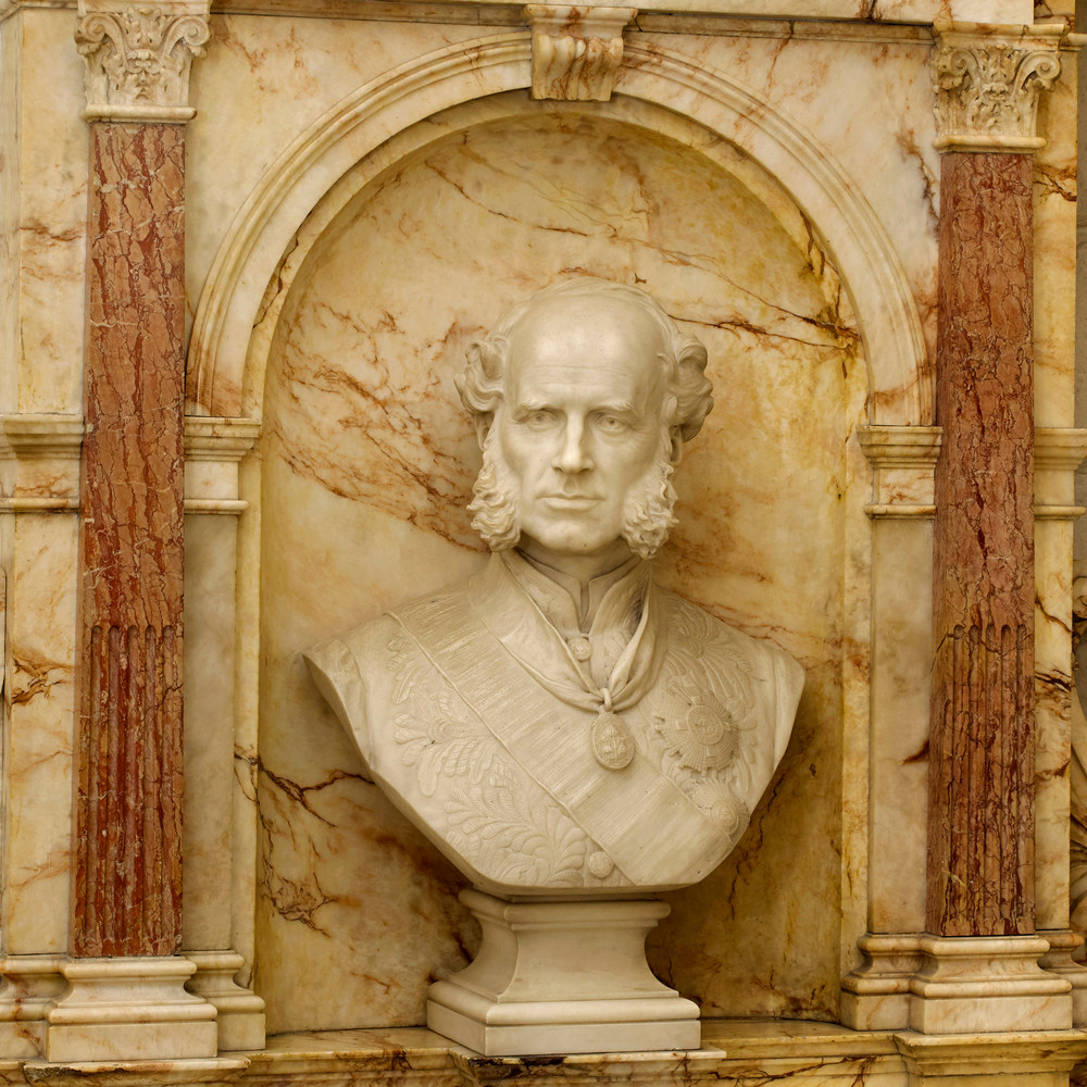 marble portrait bust of a man with a bald pate and impressive sideburns, set into a marble alcove