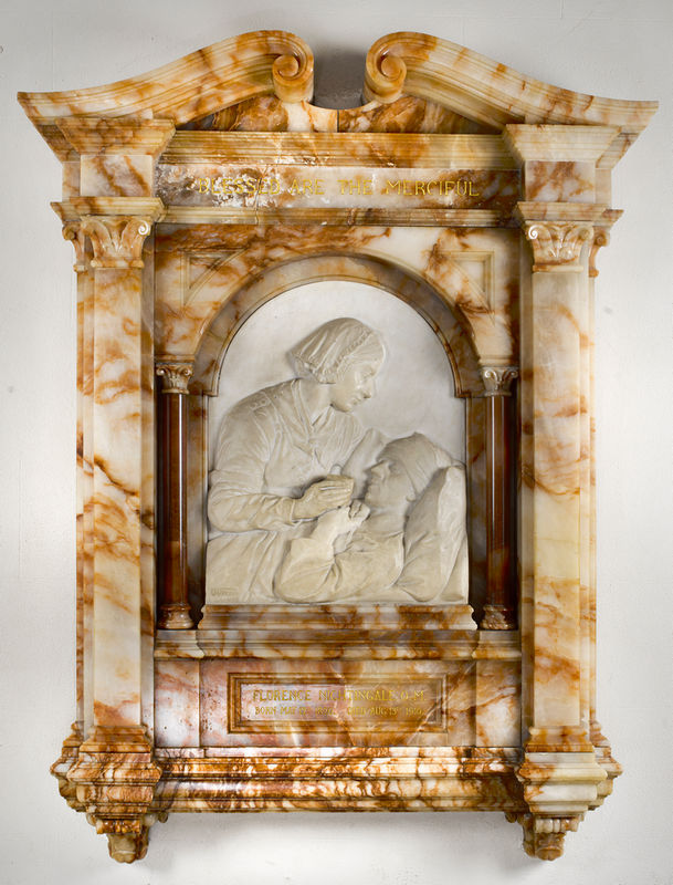 Whire marble relief showing a woman in profile lifting the head of a bed-ridden man and giving him a drink from a glass, set into an ornate surround sculpted from a marble with distinct orangey-brown markings