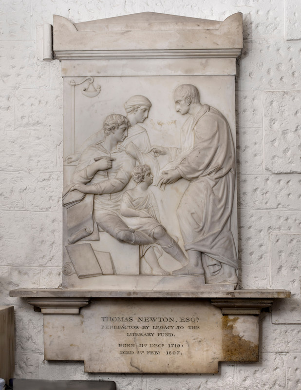 Marble wall monument  with a relief panel showing a man facing left, talking to a woman and two children, all in profile, discussing the book or papers he is holding; an inscription below