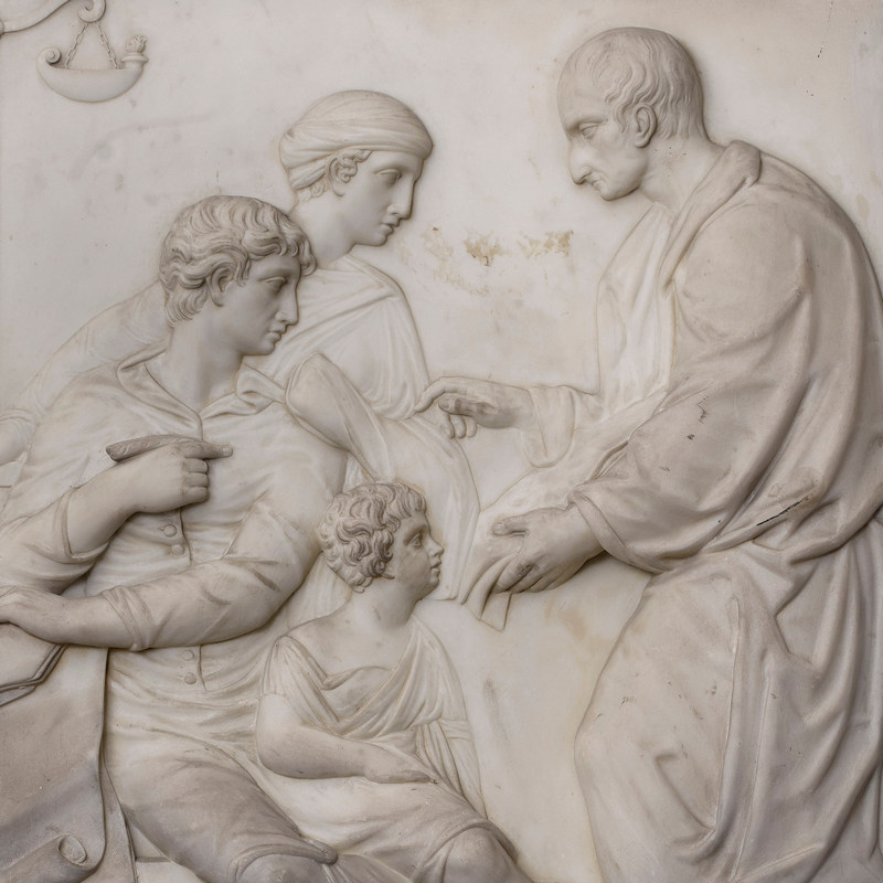 Relief sculpture detail showing a man facing left, talking to a woman and two children, all in profile