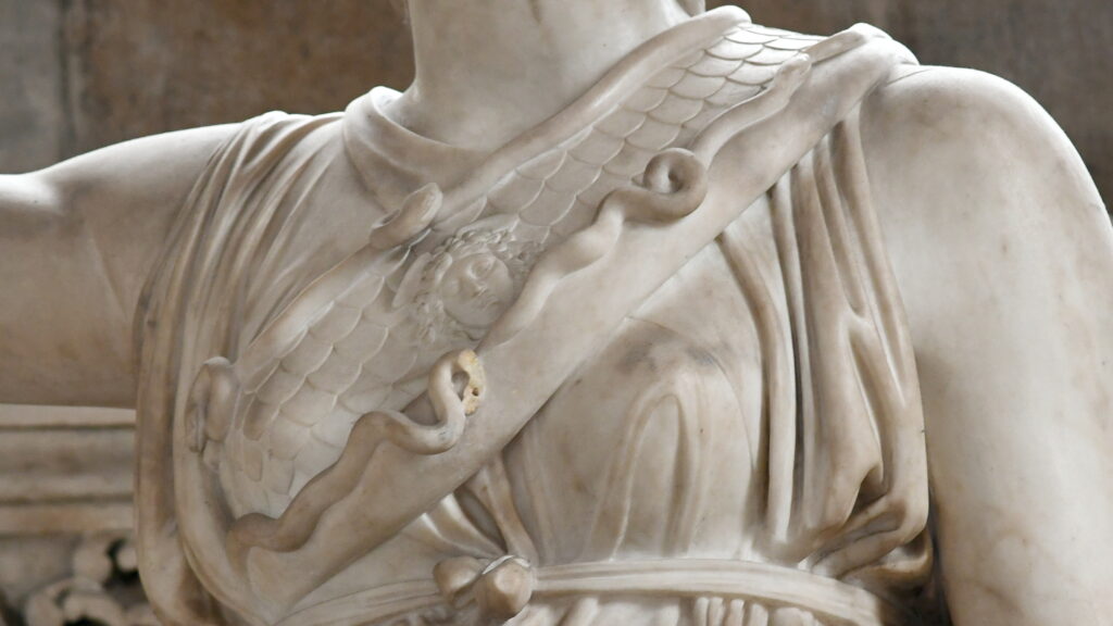 Detail of sculpted marble torso with snakes slithering along the diagonal sash