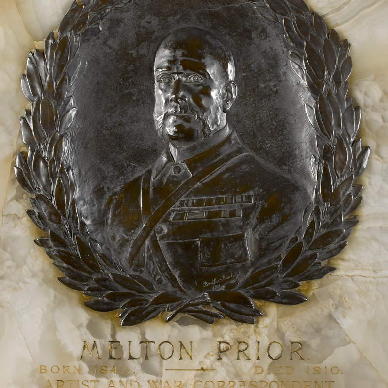 Detail of a bronze medallion featuring a portrait bust surrounded by a laurel wreath set on an onyx panel with inscription underneath