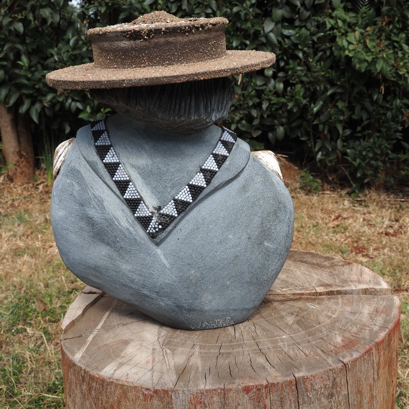 Verso - Carved stone bust of a Black man wearing a hat and wearing a beaded collar